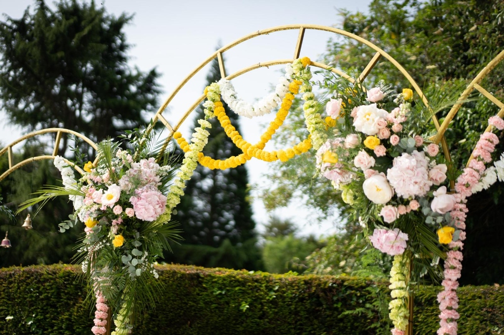 Bespoke gold floral wedding arch with fresh hydrangeas, roses and marigold garlands by Lotus Florist